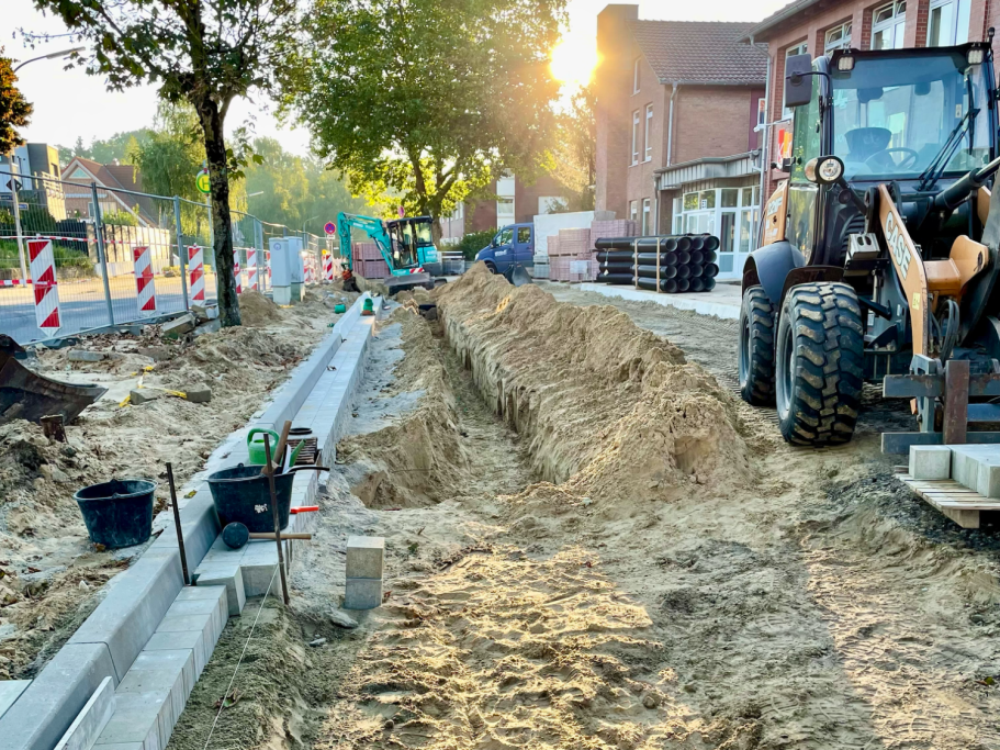 Bauarbeiten mit Graben, Bagger und Baustellenmaterial.