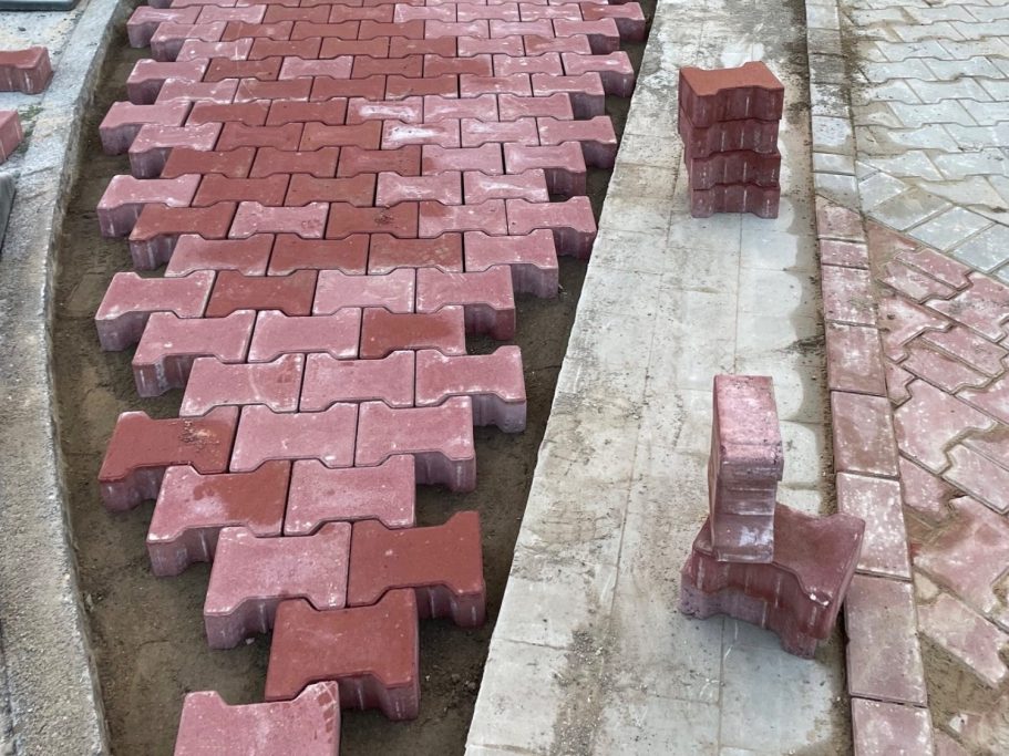 Rote Pflastersteine sind in einem Muster verlegt, mit einigen Steinen neben dem Weg.